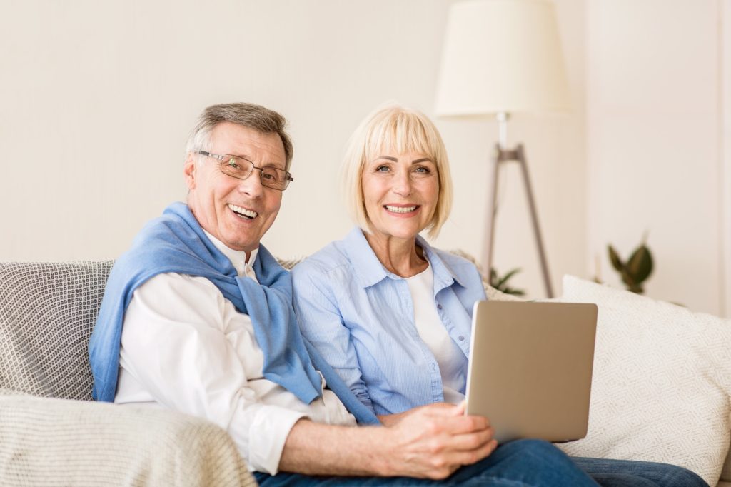joyful-elderly-couple-with-laptop-smiling-to-camera-1024x682