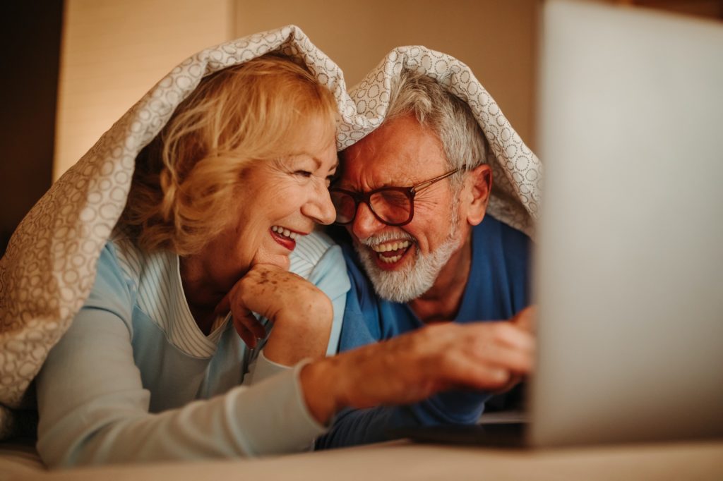 love-is-everything-smiling-elderly-couple-lying-in-bed-covered-with-blanket--1024x682