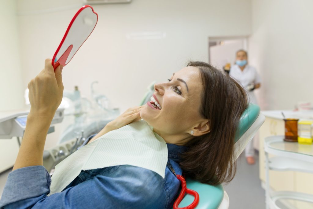 woman-patient-looking-in-the-mirror-at-the-teeth-sitting-in-the-dental-chair-1024x684